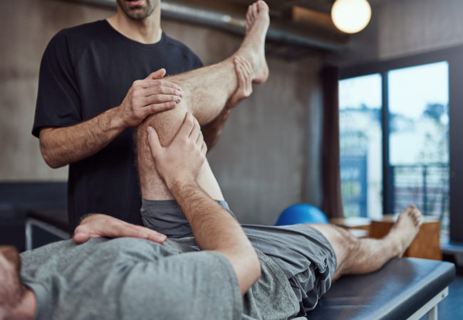 Shot of a young man visiting his physiotherapist for a rehabilitation session