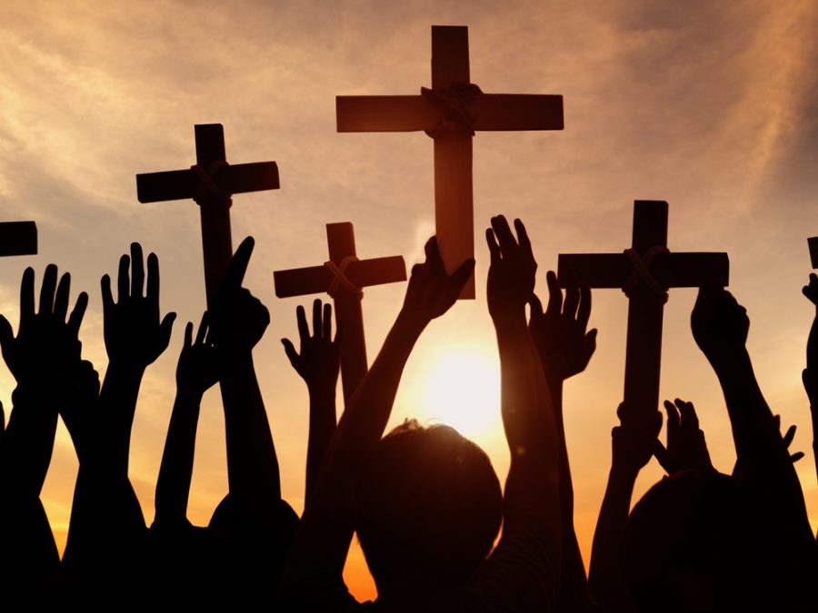 Group of People Holding Cross and Praying in Back Lit